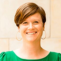 Smiling person with short hair and earrings.