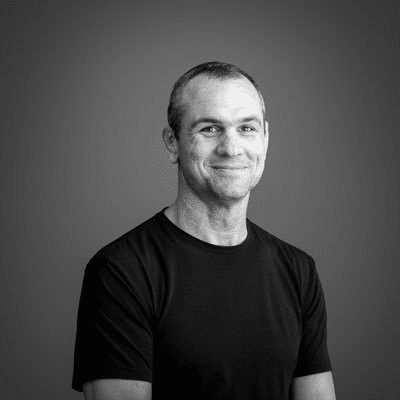 Smiling man in black shirt, monochrome portrait.