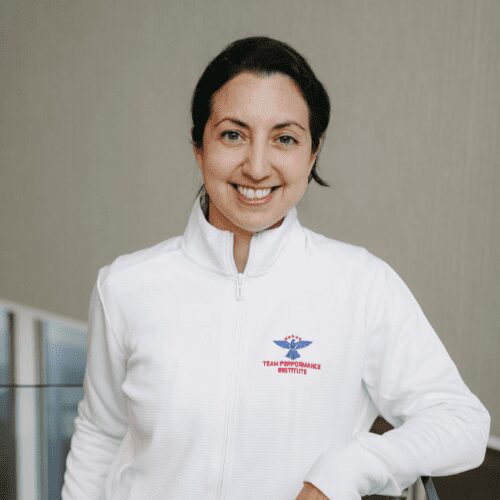 Smiling person in white jacket indoors.