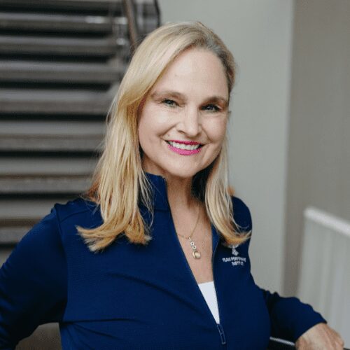 Smiling woman in blue jacket indoors.