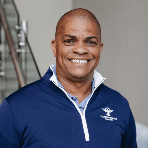 Smiling man wearing a blue jacket indoors.