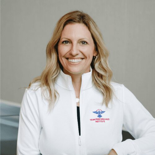 Smiling woman in white jacket indoors.